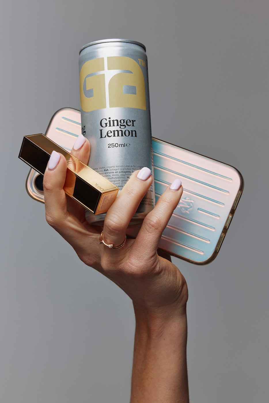 Woman holding GIGA sparkling collagen drink can together with smartphone and lipstick in a lifestyle setting